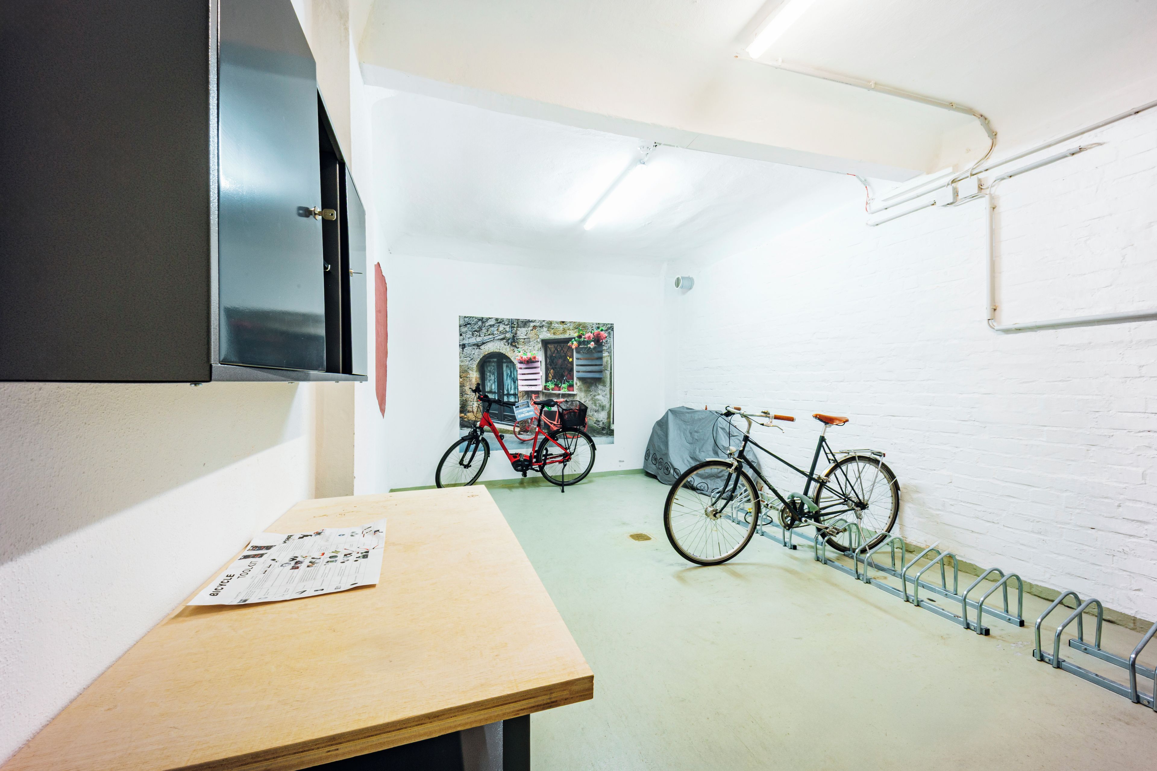 Una stanza con un tavolo di legno, una bicicletta e una TV a parete.