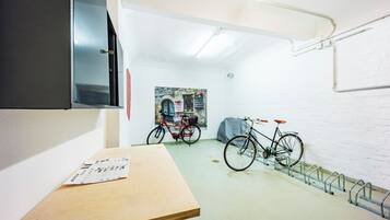 Una stanza con un tavolo di legno, una bicicletta e una TV a parete.
