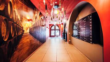 A corridor with a wine barrel wall, a wine rack, and a wine bottle display.