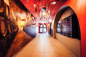 Un pasillo con un muro de barriles de vino, una bodega y una exhibición de botellas de vino.