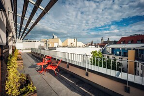 Terraza en la azotea con mesa y sillas, con vista a un paisaje urbano con varios edificios.