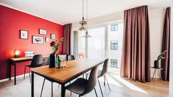 Ein moderner Essbereich mit einem Holztisch, schwarzen Stühlen, einem Laptop und einer Blumenvase.