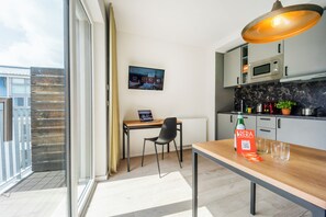 A modern kitchen with a dining area, a TV mounted on the wall, and a balcony with a view. - Brera Serviced Apartments Leipzig (Leipzig)
