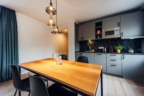 A modern kitchen with grey cabinets, a wooden dining table, and a black countertop. - Brera Serviced Apartments Leipzig (Leipzig)