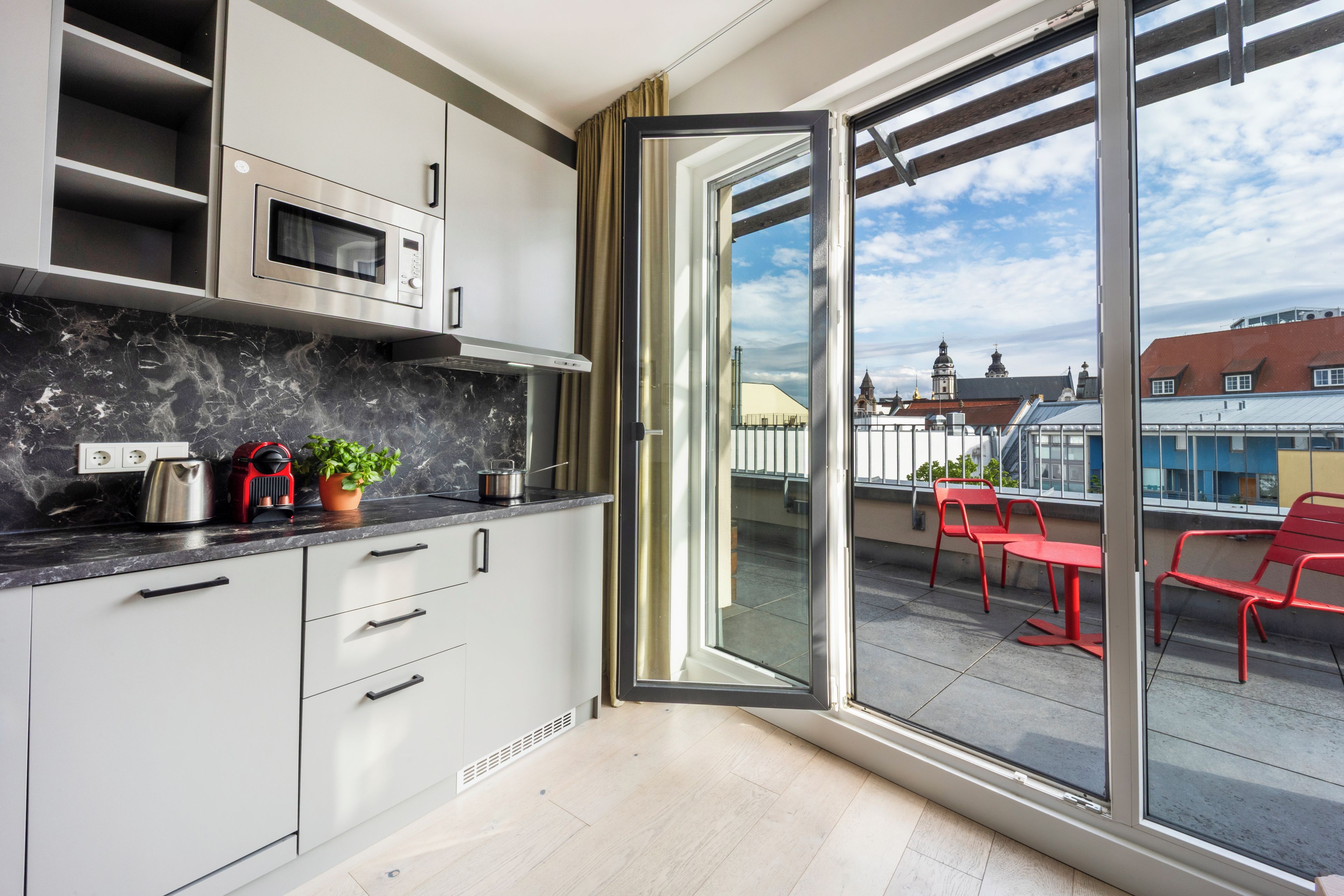 A modern kitchen with a built-in microwave, a coffee machine, and a potted plant.
