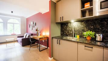 A modern kitchen with a marble countertop, a built-in oven, and a dining area with a table and chairs.