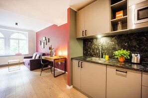 A modern kitchen with a marble countertop, a built-in oven, and a dining area with a table and chairs. - Brera Serviced Apartments Leipzig (Leipzig)