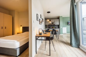 A modern hotel room with a bed, a desk, and a kitchenette. - Brera Serviced Apartments Leipzig (Leipzig)