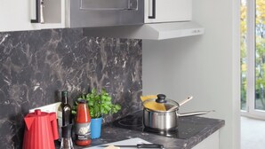 Una cocina moderna con microondas integrado, encimera de mármol y ventana con vistas al exterior.