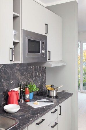 Una cocina moderna con microondas integrado, encimera de mármol y ventana con vistas al exterior.