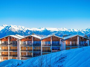 A row of wooden cabins with balconies, set against a backdrop of snow-covered mountains. - Montfort 10A by Interhome (Nendaz)