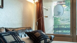 Une chambre à coucher avec un lit, une fenêtre avec des rideaux et une antenne parabolique à l’extérieur.