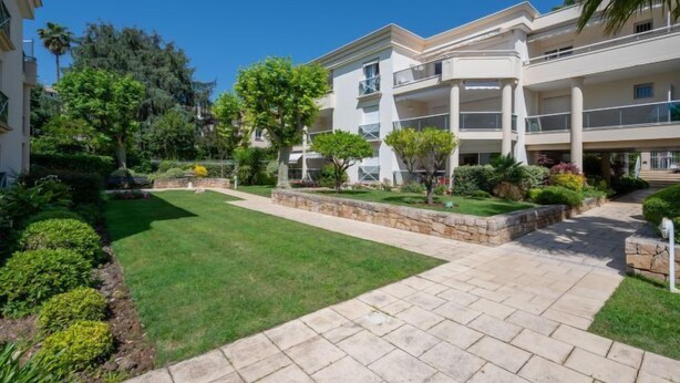 A modern multi-story building with a central courtyard, surrounded by lush greenery and a well-maintained lawn. - Eden Cap by Interhome (Antibes)