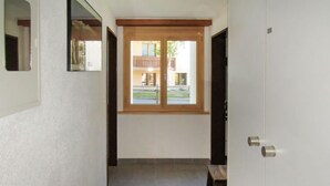 A narrow hallway with a wooden door, a window, and a bench. - Sungold by Interhome (Zermatt)
