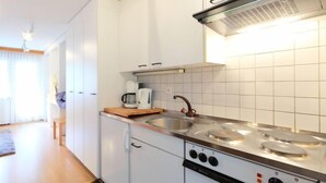 A modern kitchen with white cabinets, a stainless steel stove, and a coffee maker on the counter. - Sungold by Interhome (Zermatt)