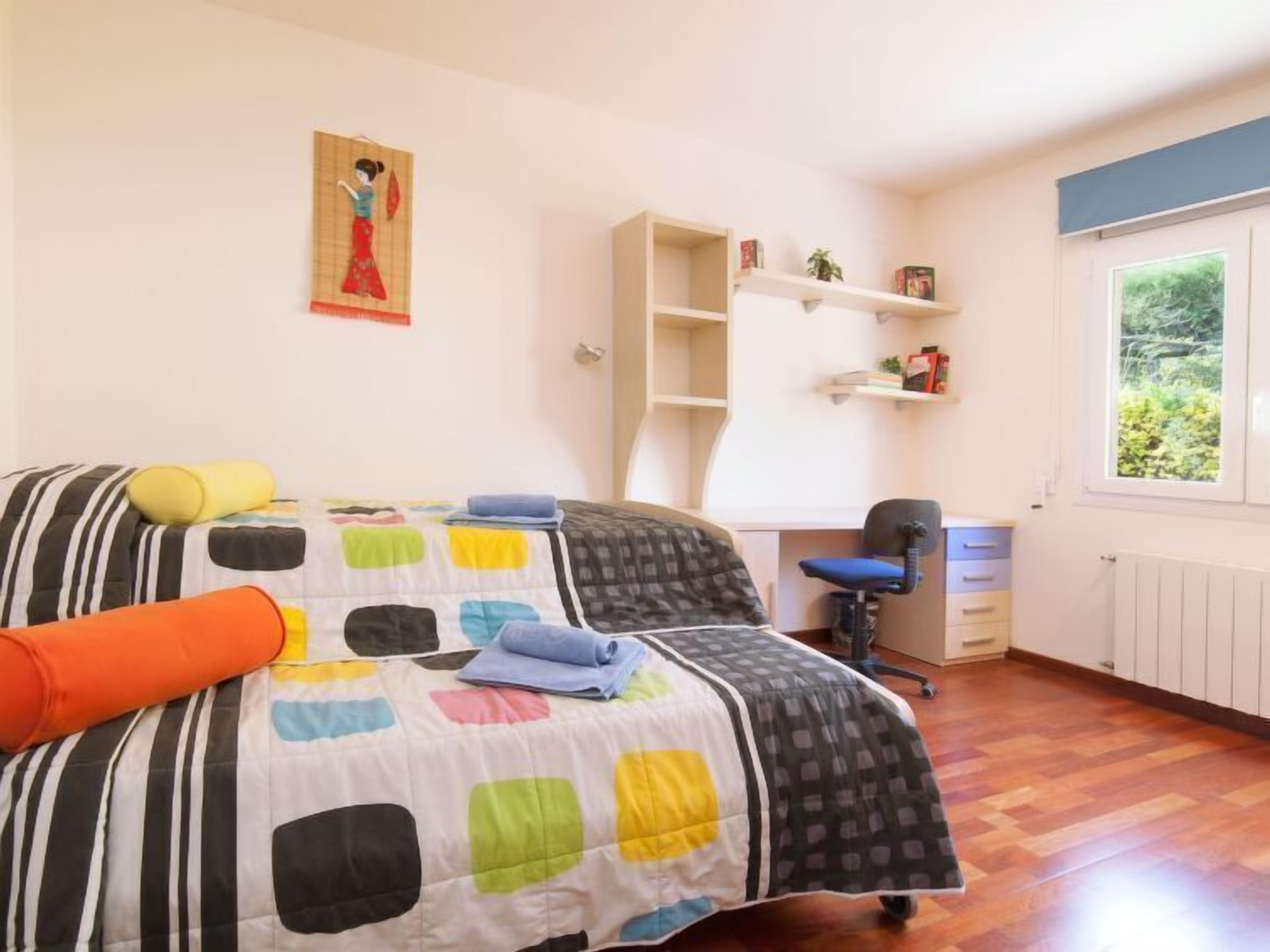Une chambre à coucher comprenant un lit, un bureau, une chaise et une fenêtre donnant sur un paysage verdoyant.