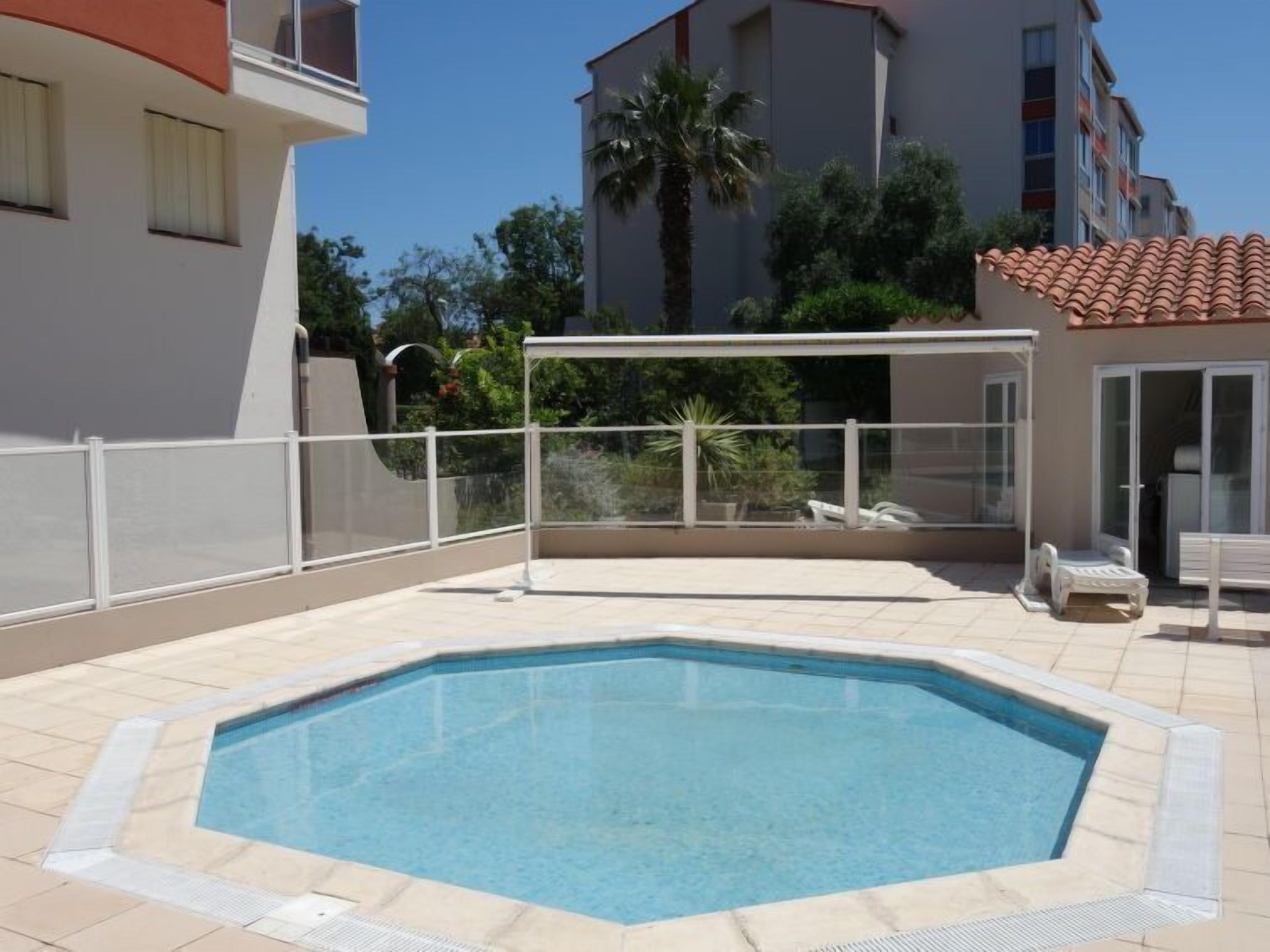 Una piscina con bordo bianco, circondata da un recinto bianco.