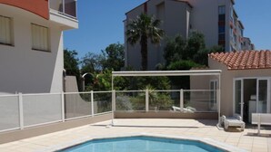 A swimming pool with a white deck, surrounded by a white fence.