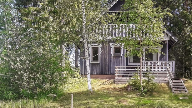 A rustic cabin with a wooden deck and a dock extending into a calm body of water. - Piilopirtti by Interhome (Kaavi)