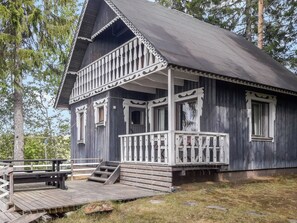 A wooden cabin with a porch and steps leading to the entrance.