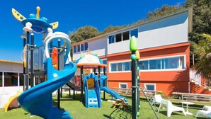 A playground with slides and climbing structures, surrounded by a building with multiple windows and a flat roof. - Apartment La Mer by Interhome (Pula)