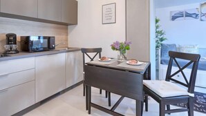 A modern kitchen with a dining area, featuring a microwave, sink, and a table with chairs. - Apartment La Mer by Interhome (Pula)
