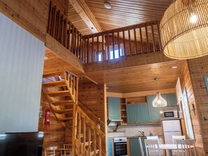 A wooden interior with a staircase, kitchen area, and a dining table. - Noukatti by Interhome (Sotkamo)