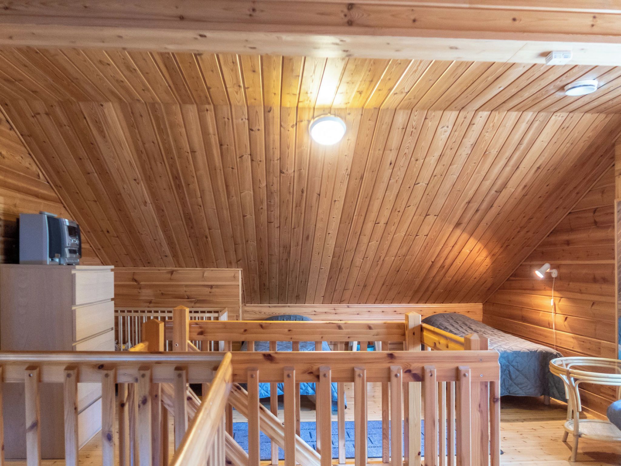 Ein Zimmer mit Holzausstattung, schrägverdeckter Decke, einem Bett, einem Schreibtisch und einem Stuhl.