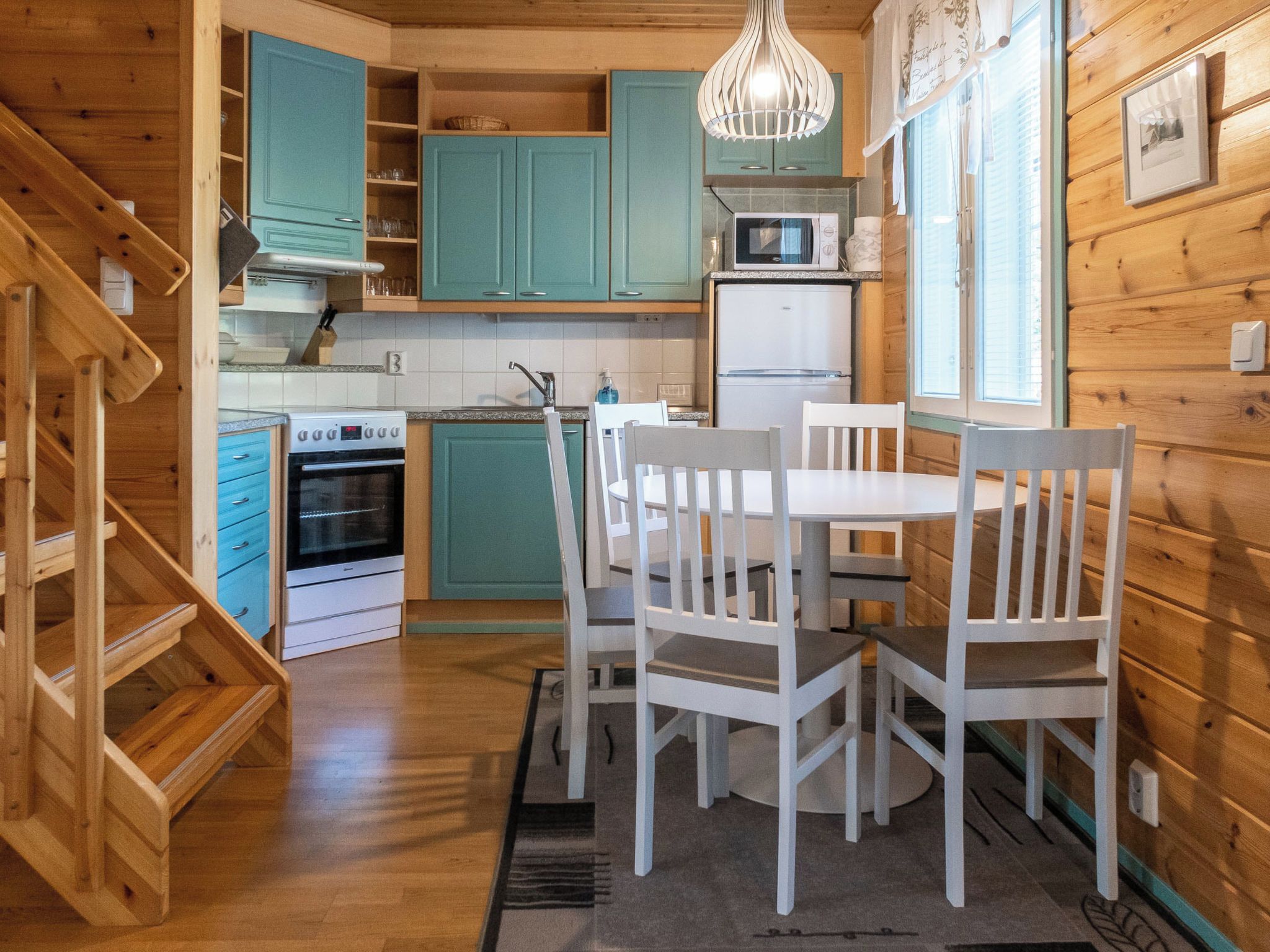 A wooden interior with a kitchen, dining area, and staircase.
