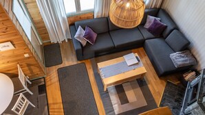 Ein modernes Interieur mit einem dunkelgrauen Sofa, einem Holztisch und einer großen gewobenen Leuchte.