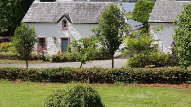 A traditional stone house with a pitched roof, a small window with a red frame, and a door. - Lorn Mill by Interhome (Balloch)