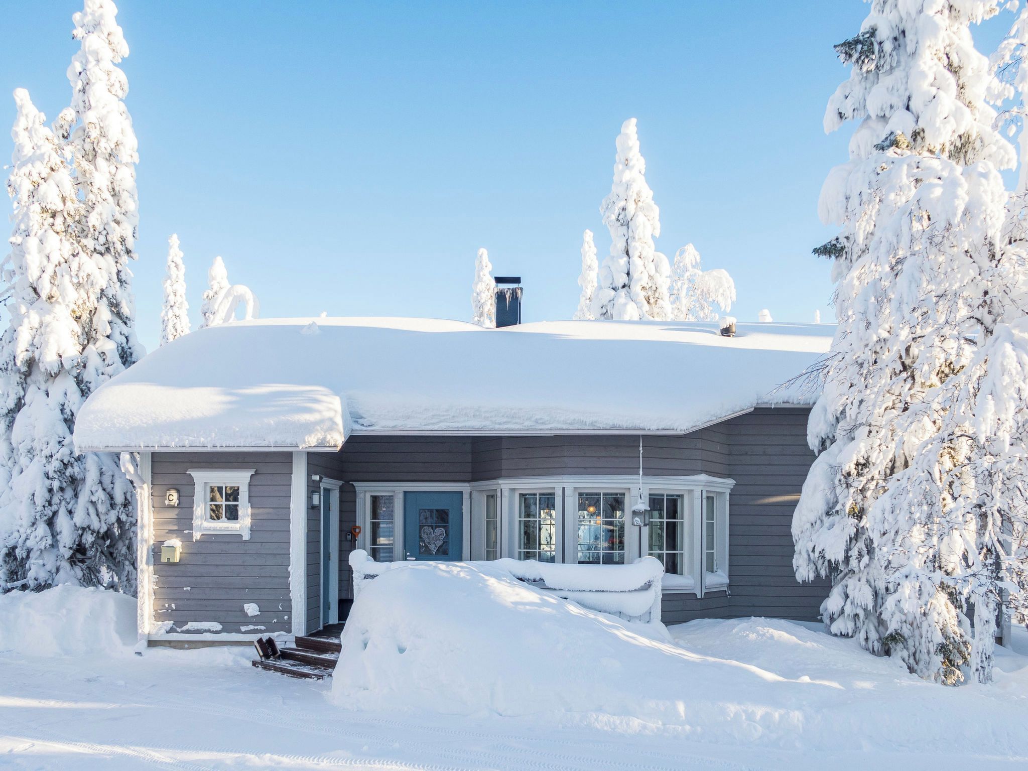 Ein mit Schnee bedecktes Haus mit Veranda und Garage.
