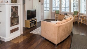 A cozy living room with a beige sofa, a TV on a wooden stand, and a fireplace.