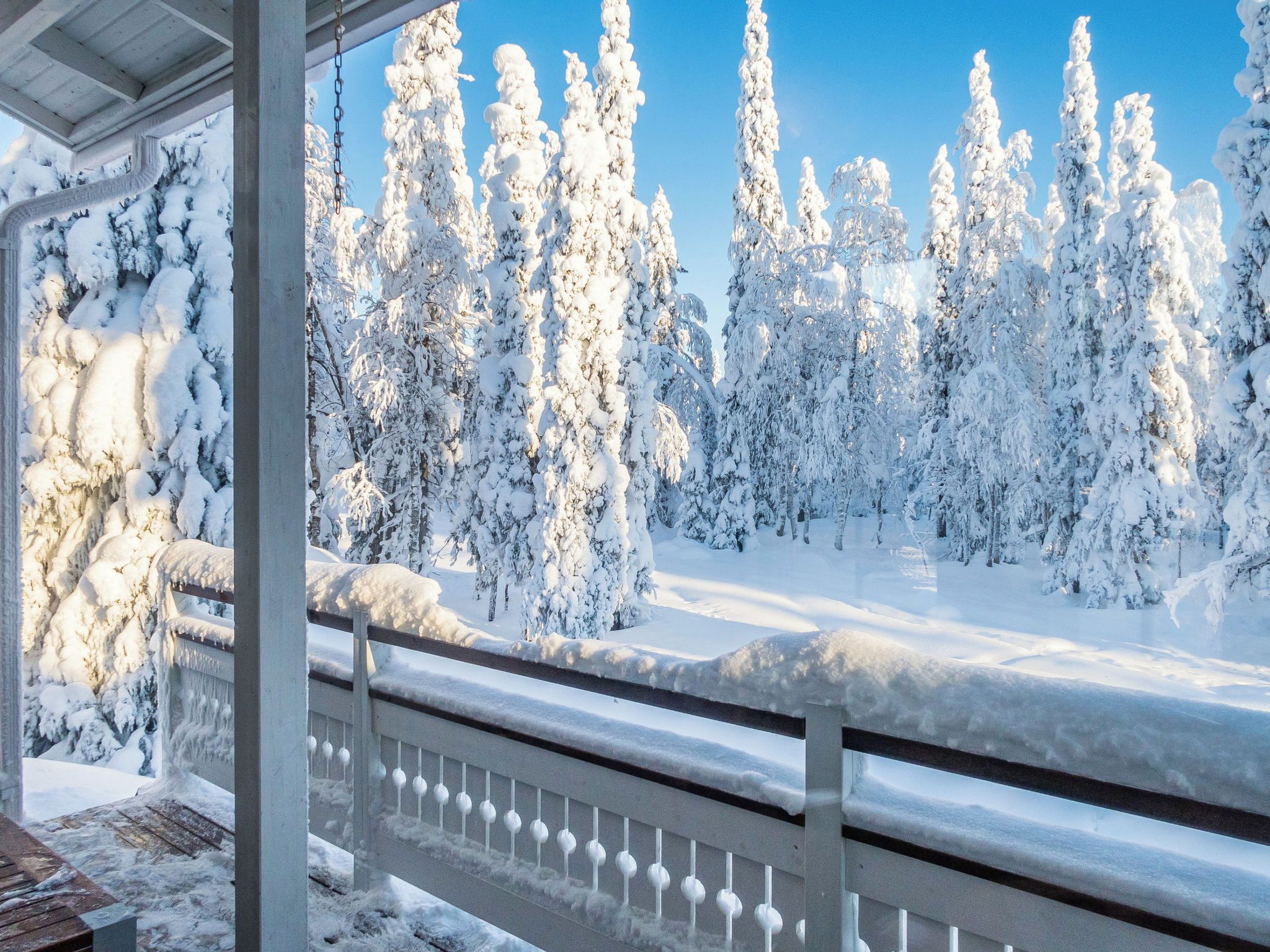 A snow-covered landscape with a wooden deck and railing.