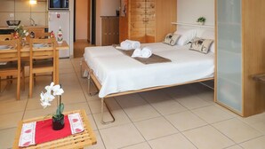 A compact bedroom with a bed, bedside tables, and a small seating area with a table and chairs. - Quille du diable 19 by Interhome (Nendaz)