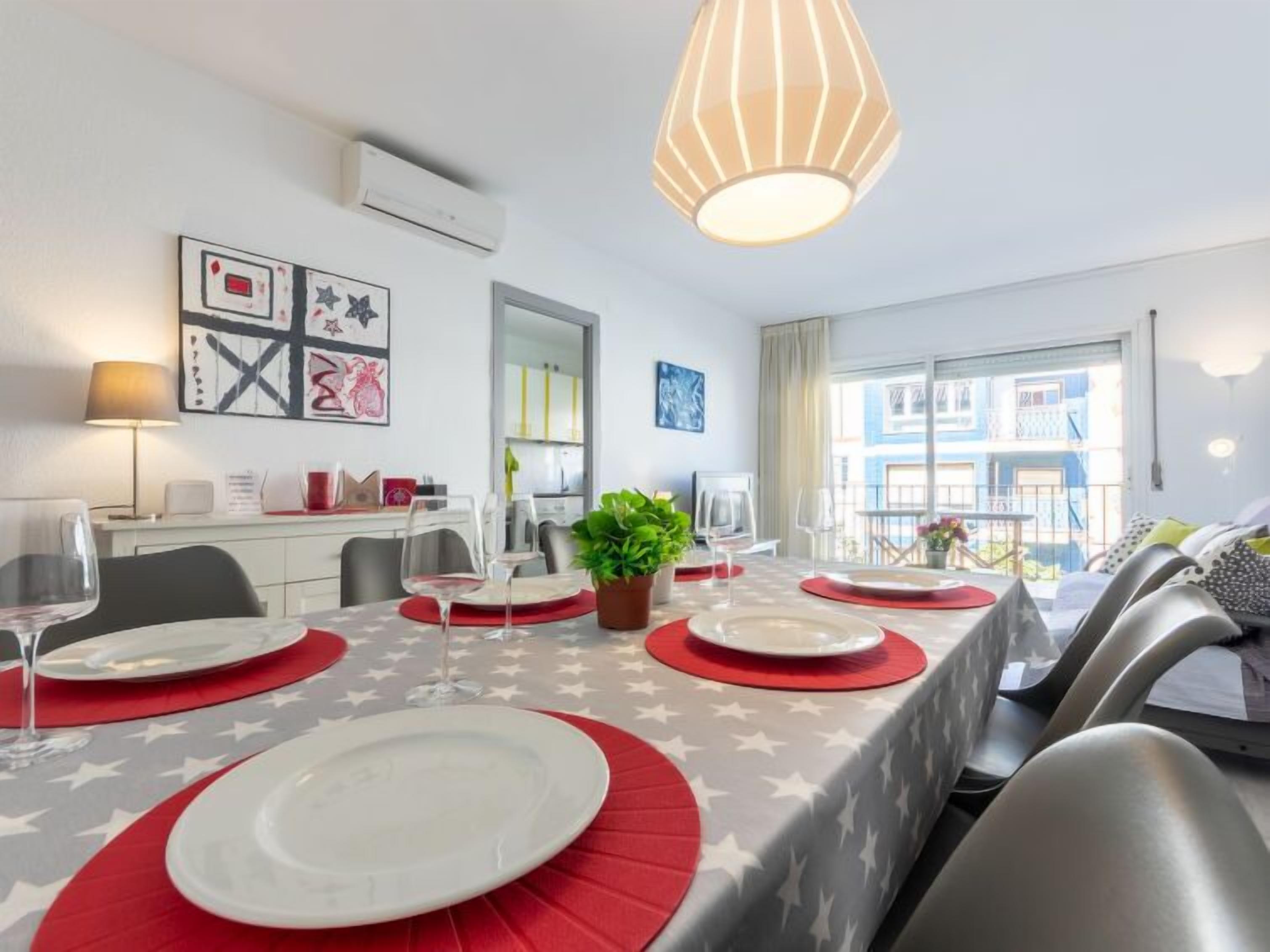 A dining area with a table set for four, a potted plant, and a view of the outside balcony.