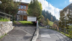 A sign for Breithorn Residence with a stone wall and a paved path leading to a building surrounded by trees. - Breithorn Residence Apt.3 by Interhome (Wengen)