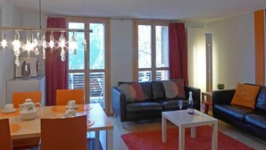 A modern living room with a dining area, a sofa, and a coffee table. - Breithorn Residence Apt.3 by Interhome (Wengen)