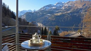 A balcony with a table set for tea, overlooking a mountainous landscape with snow-capped peaks. - Breithorn Residence Apt.3 by Interhome (Wengen)