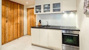 Une cuisine moderne avec un lambris en bois, des armoires blanches, un plan de travail noir et des appareils électroménagers en acier inoxydable.