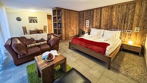 Une pièce chaleureuse avec un lit, un canapé en cuir, une petite table avec des pommes et un mur en bois.