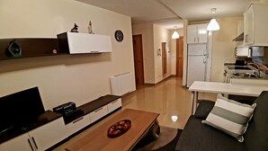 Un espace de vie compact comprenant un coin cuisine, un coin repas et un espace détente avec un canapé et une table basse.