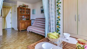 Un dormitorio acogedor con una cama y un aparador de madera, además de una mesa de comedor con un cesto de plátanos.