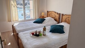 Ein Hotelzimmer mit zwei Betten, Blick auf den Yachthafen und einem Frühstücksbrettchen auf dem Bett.