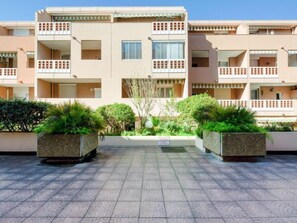 Un edifici residencial de diverses plantes amb balcons, un pati pavimentat i jardineres decoratives.