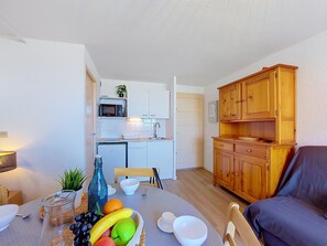 Un espace de vie compact comprenant un coin cuisine, un espace repas et un coin salon.