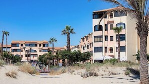 Ett hotell vid stranden med flera våningar, palmer och en sandstrand.