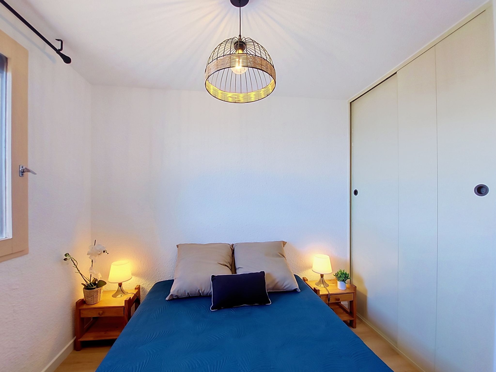 Ein Schlafzimmer mit einem Bett, Nachttischlampen, einer Hängelampe und einem Kleiderschrank.