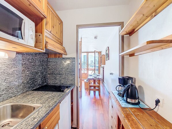 Una cocina estrecha con armarios de madera, encimera de granito y vista al área de comedor.