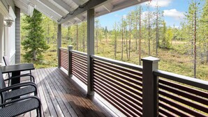 A covered outdoor deck with a wooden floor, metal railings, and a table with chairs.
